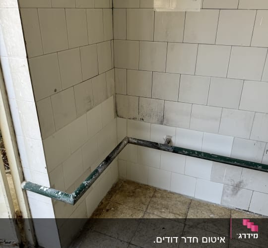 קיר אריחים לבנים עם כתמי עובש ורטיבות בפינת החדר
